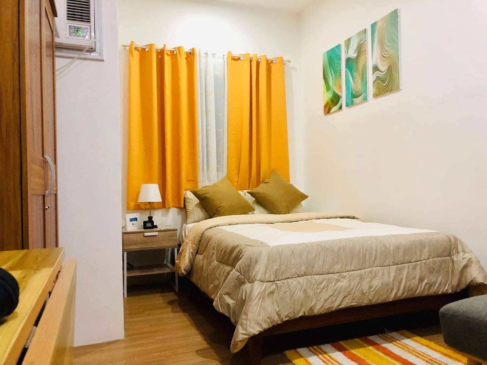 The bedroom: a queen bed, wardrobe and window with orange curtains