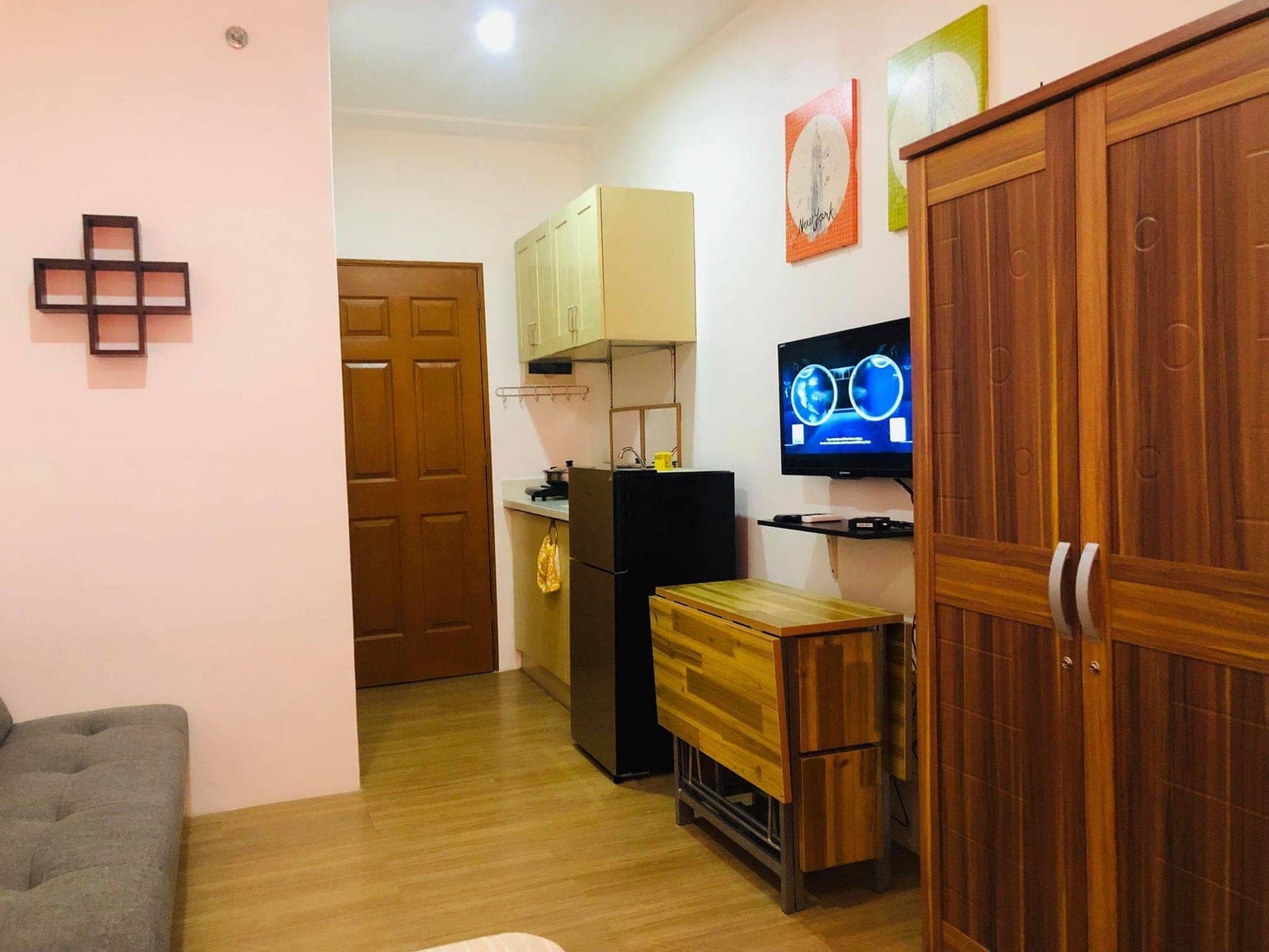 The kitchenette with fridge, wall TV and wardrobe